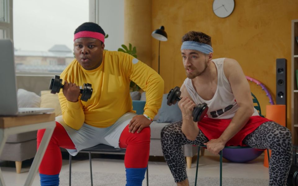Two people at home following an online fitness video