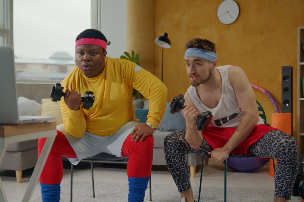 Two people at home following an online fitness video